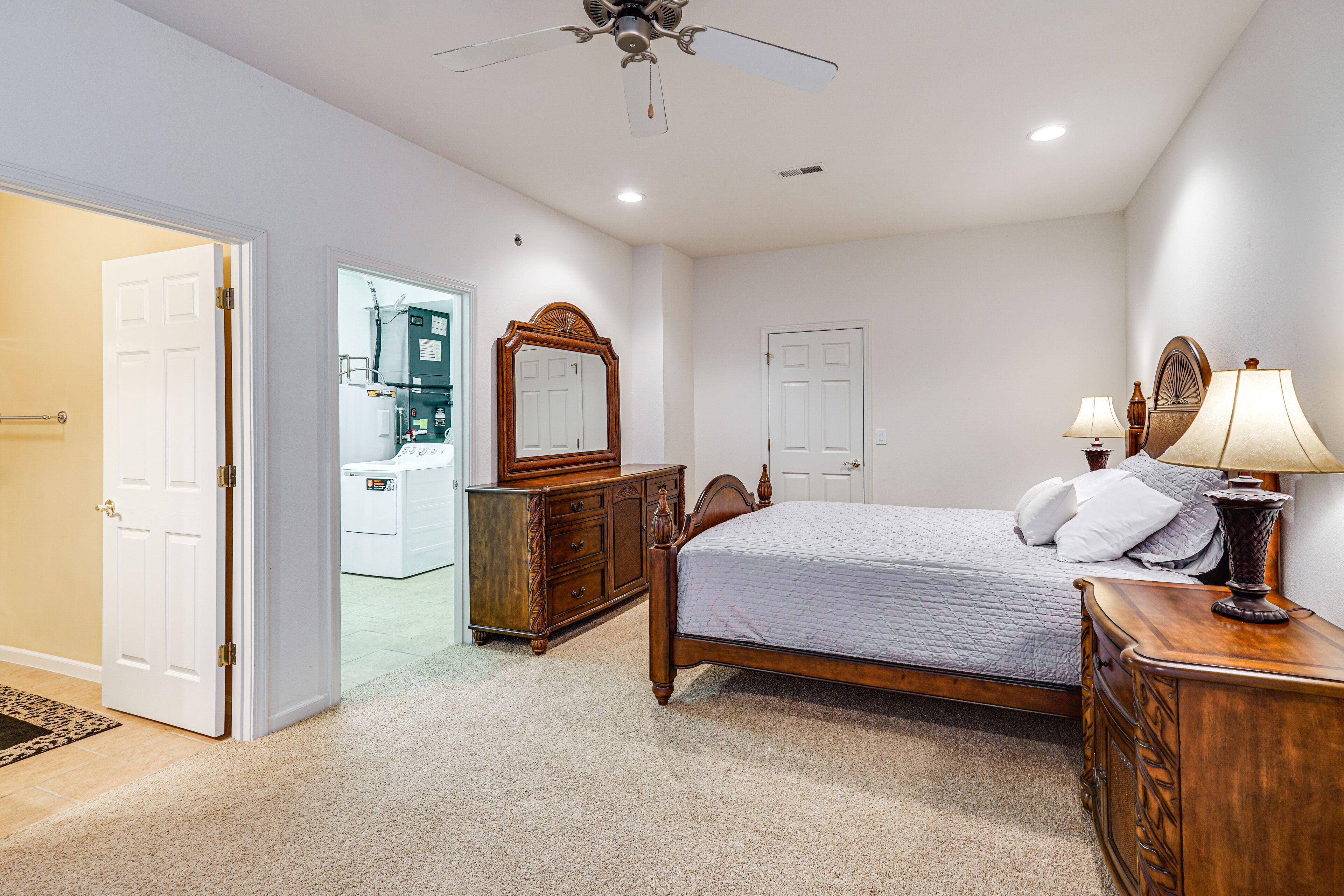 Quarto com cama, cômoda, espelho e ventilador de teto.