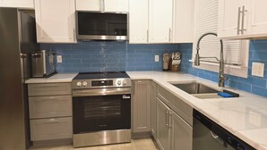 A modern kitchen with stainless steel appliances, white cabinets, and blue backsplash tiles. - Updated 3Bedroom. 5beds group ready.Walk to the Casino and play game of Pool. (Springfield)