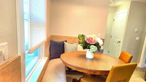 A dining area with a round wooden table, cushioned bench, and a vase of flowers. - Updated 3Bedroom. 5beds group ready.Walk to the Casino and play game of Pool. (Springfield)
