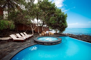 A pool area with lounge chairs, a hot tub, and a view of the ocean. - Hotel Villa Escalesia Galapagos (Puerto Ayora)