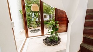A modern interior with a large glass door leading to an outdoor garden area. - Hotel Villa Escalesia Galapagos (Puerto Ayora)