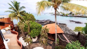 A wooden deck with a curved railing, surrounded by tropical plants and a small pool. - Hotel Villa Escalesia Galapagos (Puerto Ayora)