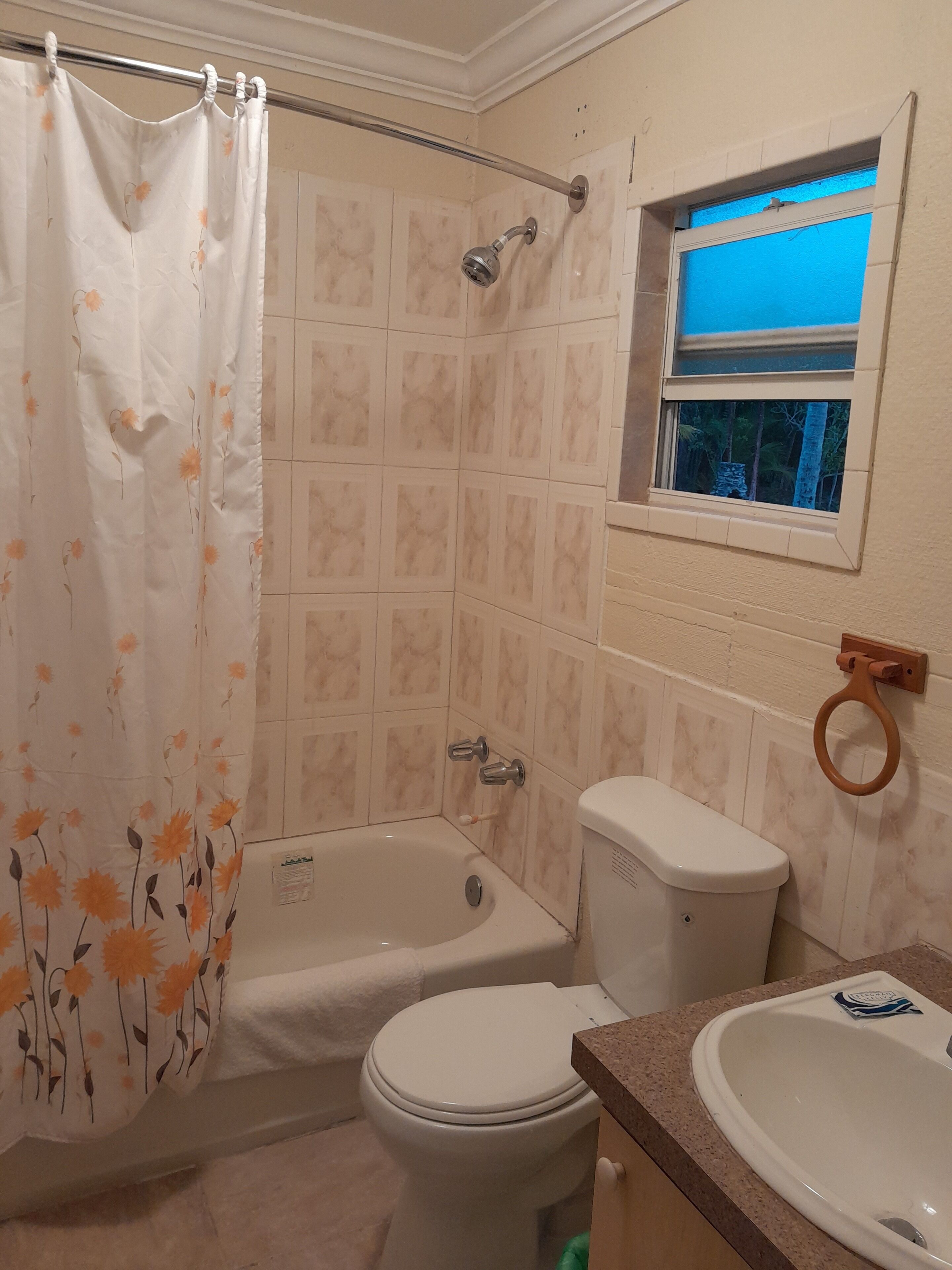 A bathroom with a shower curtain, a bathtub, a toilet, and a sink.