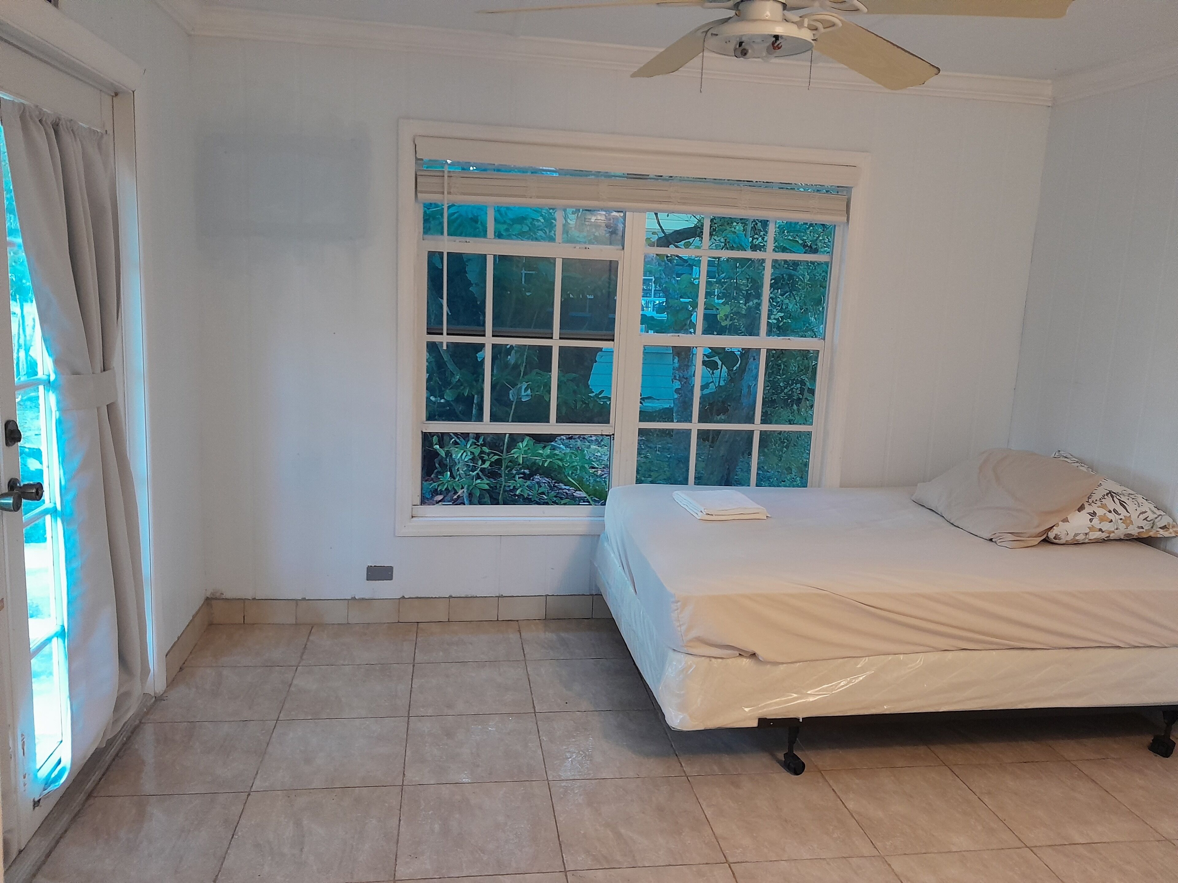 A room with a bed, a window, and a ceiling fan.