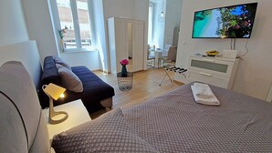 Een moderne hotelkamer met een bed, een bank, een televisie en een bureau.