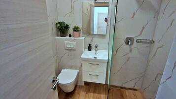 A bathroom with a toilet, sink, and mirror.