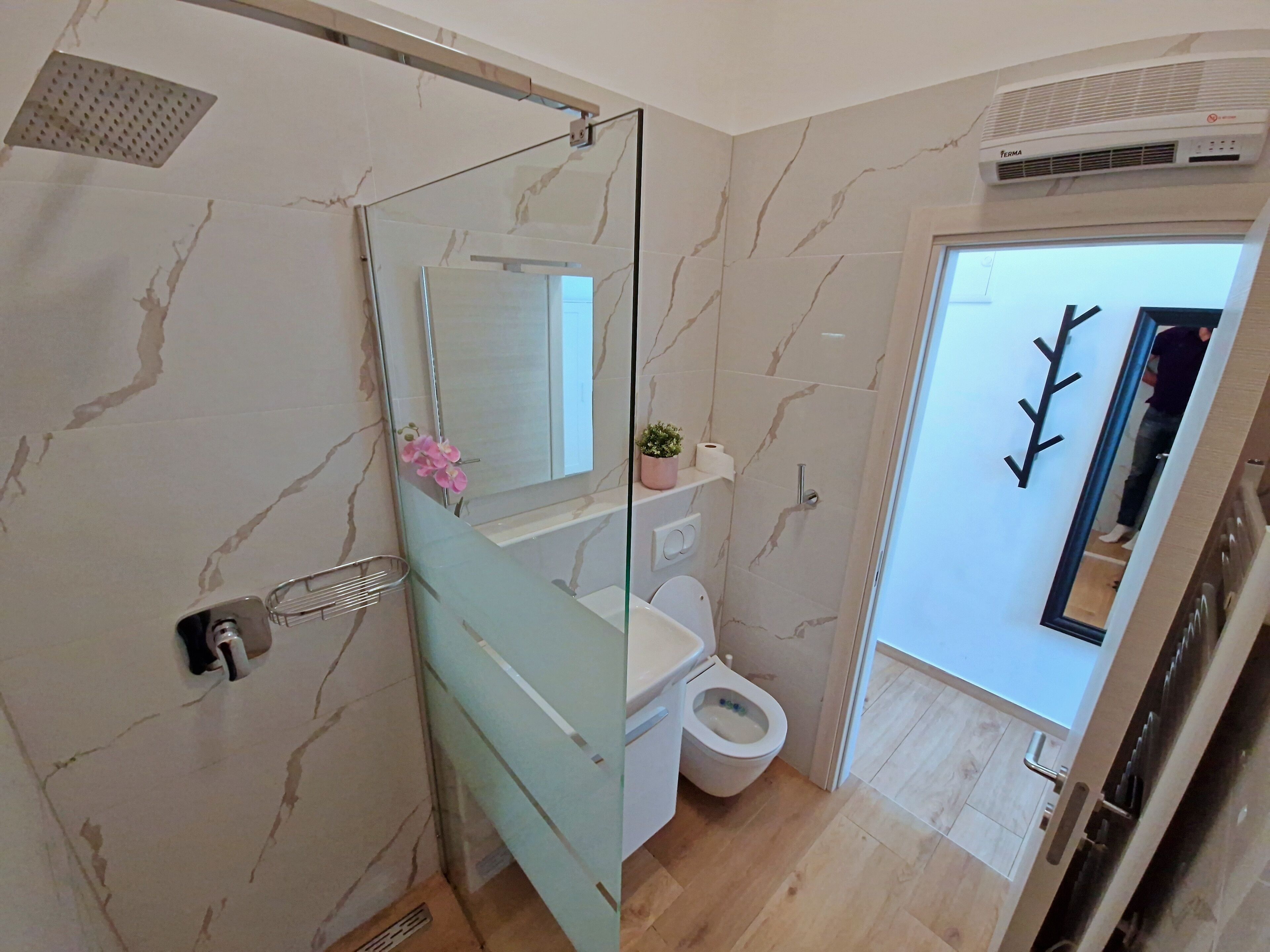 A modern bathroom with a glass shower enclosure, a toilet, and a sink.
