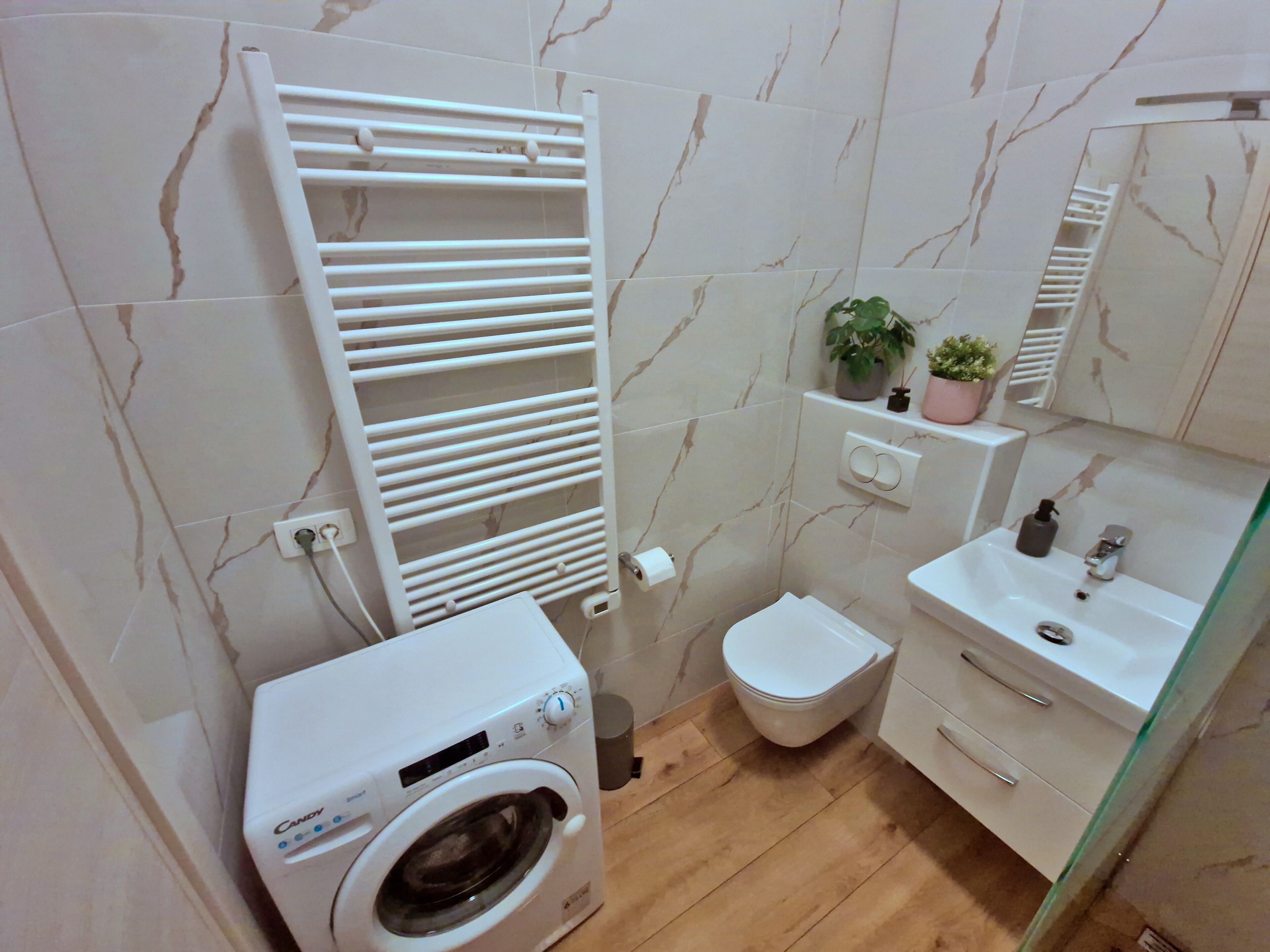 A modern bathroom with a built-in washing machine, a toilet, a sink, and a mirror.