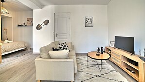 A modern living room with a sofa, a coffee table, a TV, and a door. - L'escapade Fourasine - Heart of Fouras (Fouras)