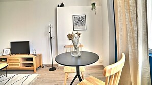 A modern living room with a round table, a TV on a wooden stand, and a framed artwork on the wall. - L'escapade Fourasine - Heart of Fouras (Fouras)