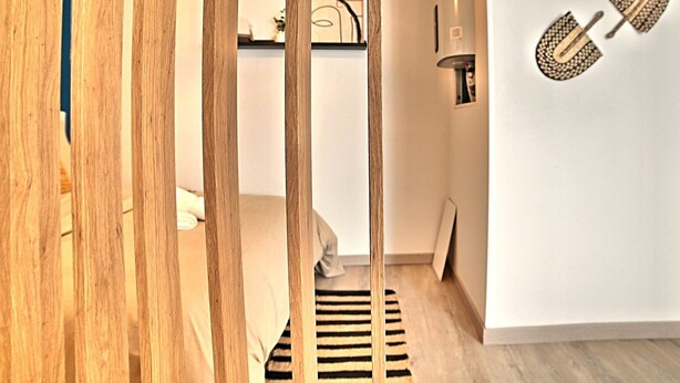A modern interior with a wooden partition, a striped rug, and a wall-mounted light fixture. - L'escapade Fourasine - Heart of Fouras (Fouras)