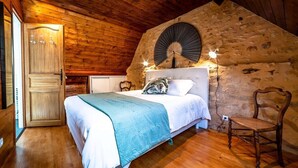 Een kamer met houten lambrisering, een bed, een ventilator en een stoel.