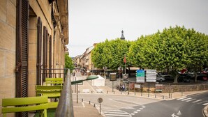 A street view with a green bench, a signpost with directions, and a building with a tower in the background. - Le Sarladais - Air conditioning and parking (Sarlat-la-Canéda)