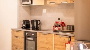 A compact kitchen with wooden cabinets, a built-in oven, a microwave, and a coffee maker. - Le Sarladais - Air conditioning and parking (Sarlat-la-Canéda)