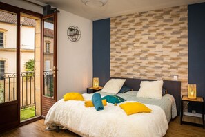 Un dormitorio con cama, mesitas de noche, un reloj de pared y vistas a través de un ventanal.