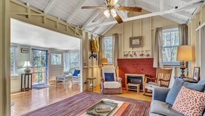 A spacious living room with a fireplace, wooden flooring, and a ceiling fan.