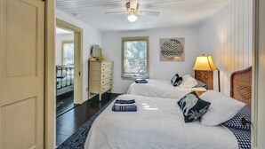 A hotel room with two beds, a ceiling fan, a window with blinds, a bedside lamp, and a decorative wall piece. - Orr's Island Ocean Views (Orr's Island)