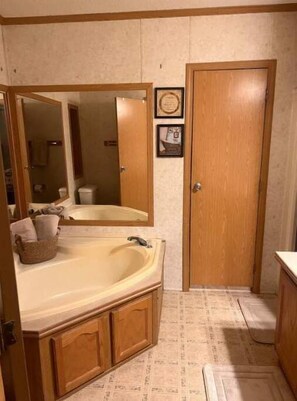 A bathroom with a bathtub, wooden cabinets, a mirror, and a door.