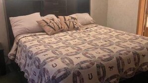 A bed with a patterned bedspread, a headboard, and two wall-mounted lamps. - 4-bedroom farm stay 20 minutes from Cooperstown All Star Village Fields (Morris)