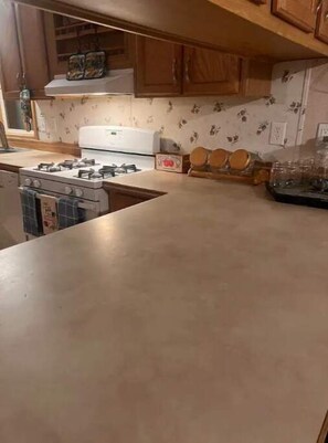 Une cuisine avec des meubles de rangement en bois, une cuisinière et un plan de travail.