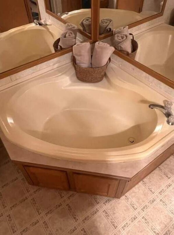 A bathroom with a large, freestanding bathtub, a mirror, and a towel rack with folded towels.