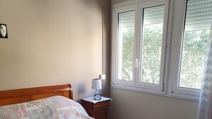 Une chambre à coucher avec un lit en bois, une table de chevet avec une lampe et une fenêtre avec des stores.