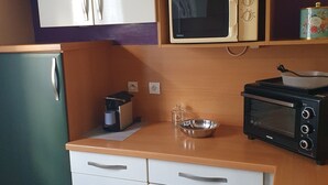 Une cuisine compacte équipée d’un four à micro-ondes, d’un grille-pain et d’un petit réfrigérateur.