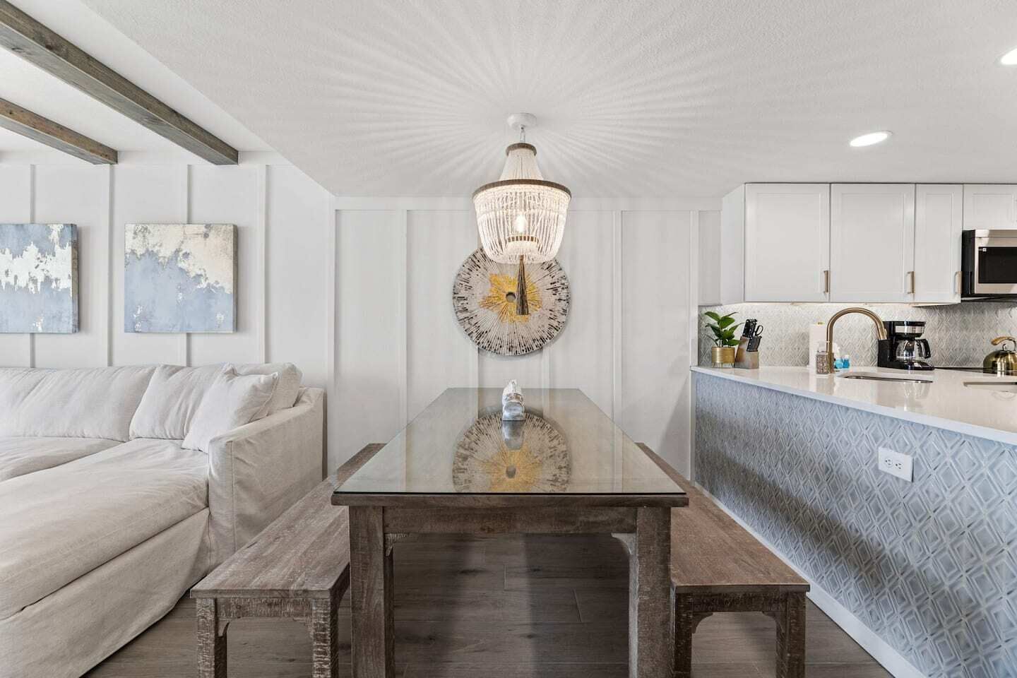 Une cuisine moderne dotée d’un îlot central, de meubles blancs et d’un lustre.