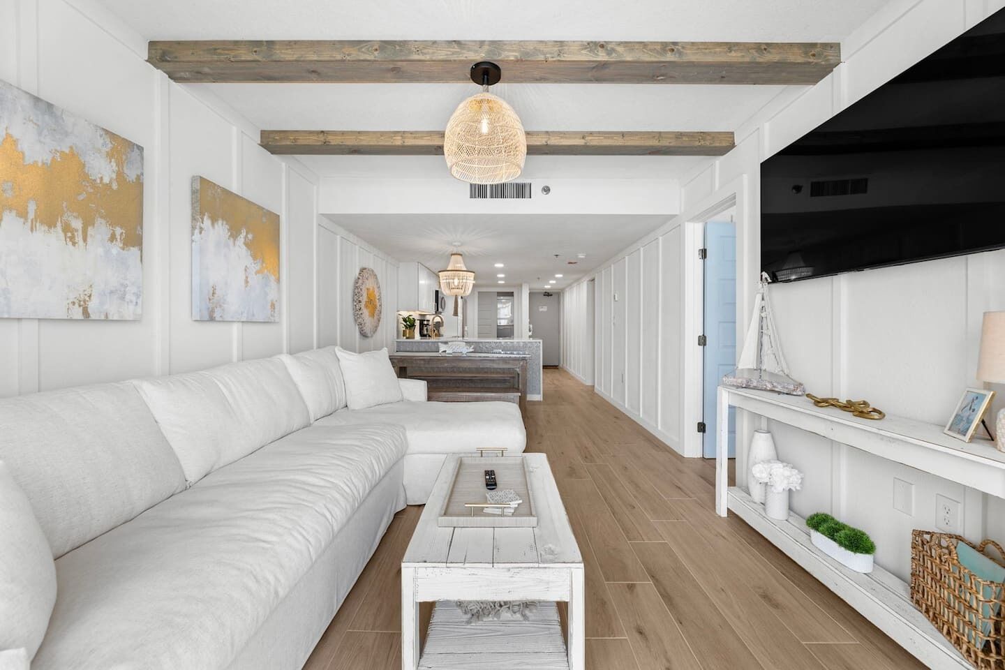 A modern living room with a white sofa, wooden coffee table, and a TV on the right.