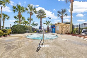 A swimming pool area with a water fountain, surrounded by palm trees and a Pepsi sign.