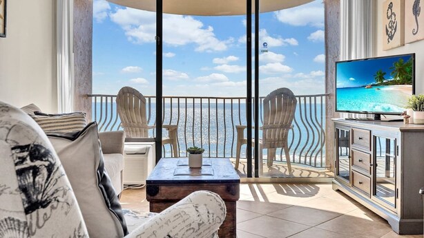 A balcony with a view of the sea, furnished with chairs and a table, and a TV on a cabinet. - Direct Ocean Front w/washer and dryer! (Myrtle Beach)