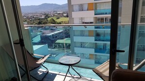 Ein Balkon mit Glasgeländer, einem kleinen runden Tisch und zwei Stühlen.