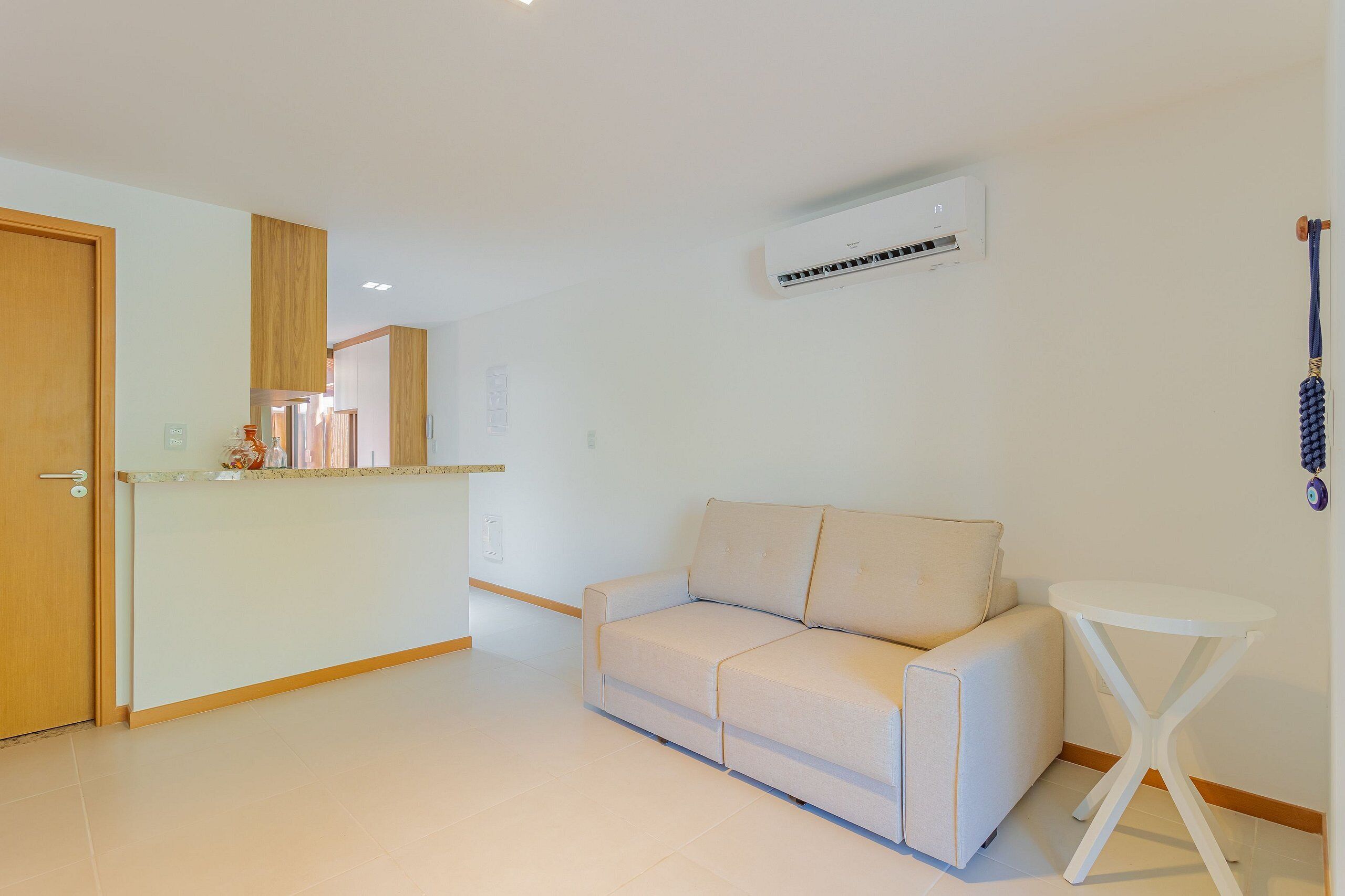 Ein modernes Wohnzimmer mit einer Couch, einem kleinen weißen Tisch und einer Klimaanlage an der Wand.