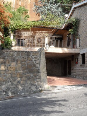 A stone building with a balcony, a stone wall, and a paved area. - Casa Serafina Typical Three-room Apartment Historic Green Area (Orvieto)
