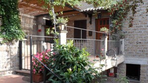 A stone building with a balcony, steps leading to the entrance, and potted plants. - Casa Serafina Typical Three-room Apartment Historic Green Area (Orvieto)