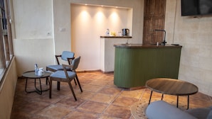 A small, cozy room with a green bar counter, two chairs, a round table, and a sofa. - Saraya Locanda (Salt)
