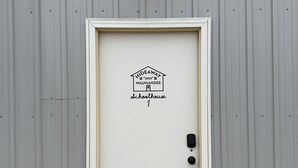 Une porte blanche avec une pancarte indiquant : « Hideaway Inn, ancienne école de Waumanee, bâtiment 1 ».