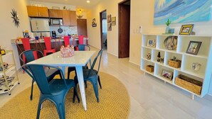 A modern kitchen with wooden cabinets, a white refrigerator, and a dining area with a white table and blue chairs. - CASA JOY  
Beautifuly decorated, Great location & Perfect escape to los Cabos.
 (Cabo San Lucas)