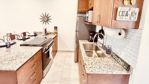 A modern kitchen with granite countertops, wooden cabinets, a stainless steel sink, and a decorative clock. - CASA JOY  
Beautifuly decorated, Great location & Perfect escape to los Cabos.
 (Cabo San Lucas)