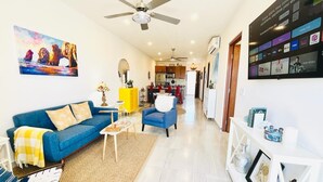A modern living room with a blue sofa, a coffee table, and a TV mounted on the wall displaying various channels. - CASA JOY  
Beautifuly decorated, Great location & Perfect escape to los Cabos.
 (Cabo San Lucas)