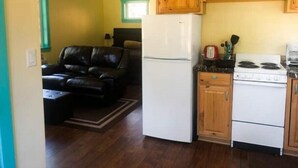 A compact living space with a kitchenette, a sofa, and a refrigerator. - Cabin Getaway (Cashmere)