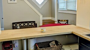 A cozy dining area with a wooden table, chairs, and pendant lights. A sign on the wall reads "Live love & let go."