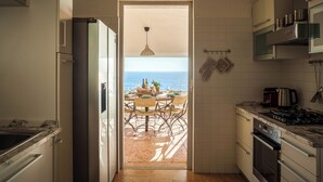 Een keuken met uitzicht op zee door een open deur.