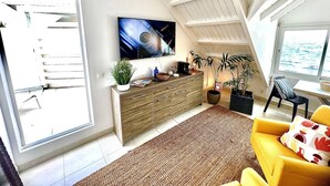 A modern living room with a large TV, wooden cabinet, and a yellow sofa.