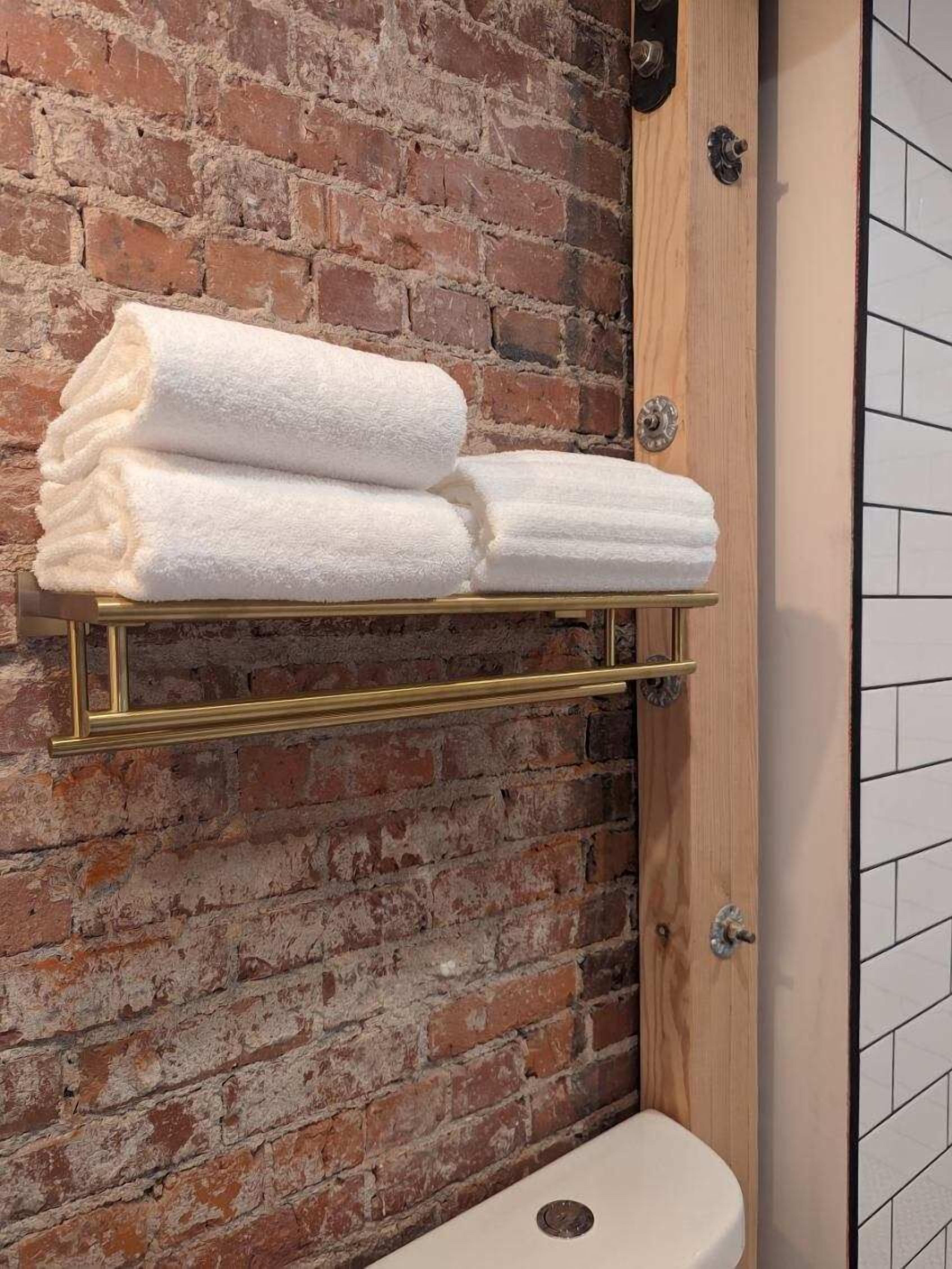A bathroom with a brick wall, a wooden door, and a white toilet.