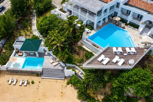 Ein Resort mit mehreren Schwimmbecken, einem Strandbereich und einer Dachterrasse mit Liegestühlen.