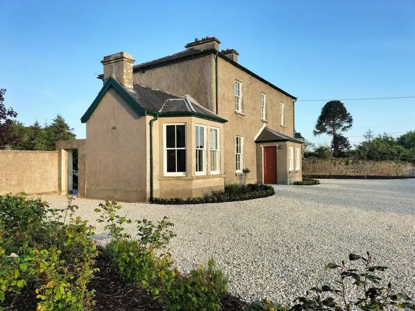 A two-story house with a gravel driveway and a red door. - The Old Kirk and Manse, Hollymount (Hollymount)