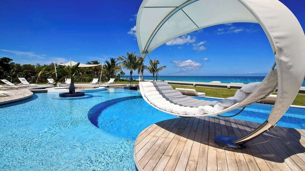 A poolside area with a curved white canopy, lounge chairs, and a view of the ocean. - Villa C’est La Vie – Luxury Beachfront Villa on Plum Bay, St. Martin with Private Chef (Marigot)