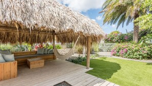 A wooden deck with a thatched roof structure, a hammock, and a seating area with cushions. - The Pearl of Jan Thiel 1 – Luxury Designer Villa with Private Pool & Resort Facilities in Curaçao (Willemstad)