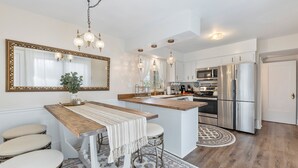 A modern kitchen with a wooden island, stainless steel appliances, and a large mirror. - - Beautiful Condo - King Bed - Free Waffle Breakfast - (Geneva)